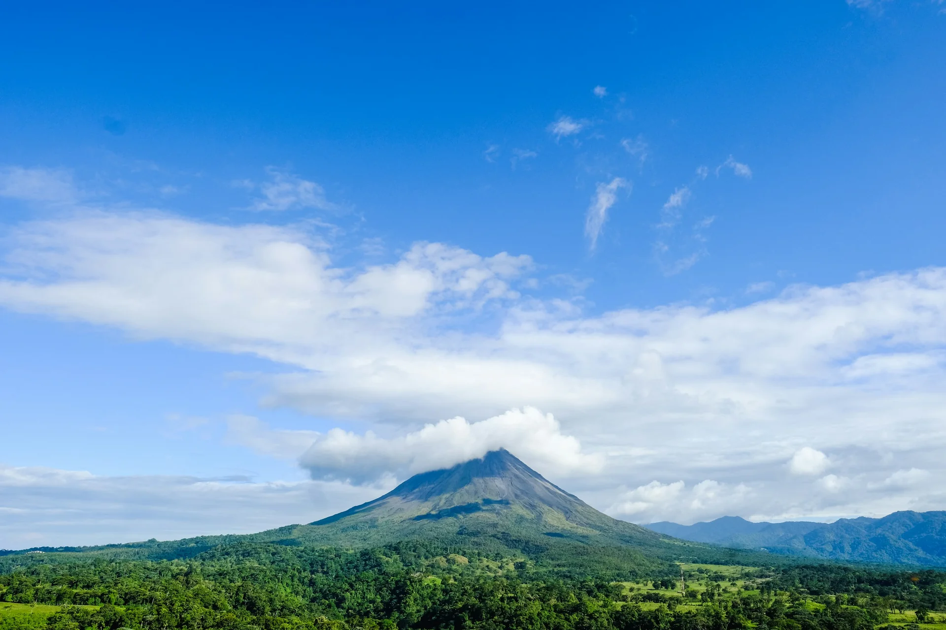 Vulkan Arenal vor grüner Landschaft und Wolken in Costa Rica